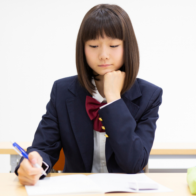 ノートに赤ペンで添削を受けた答案を見ている中学生のイラスト